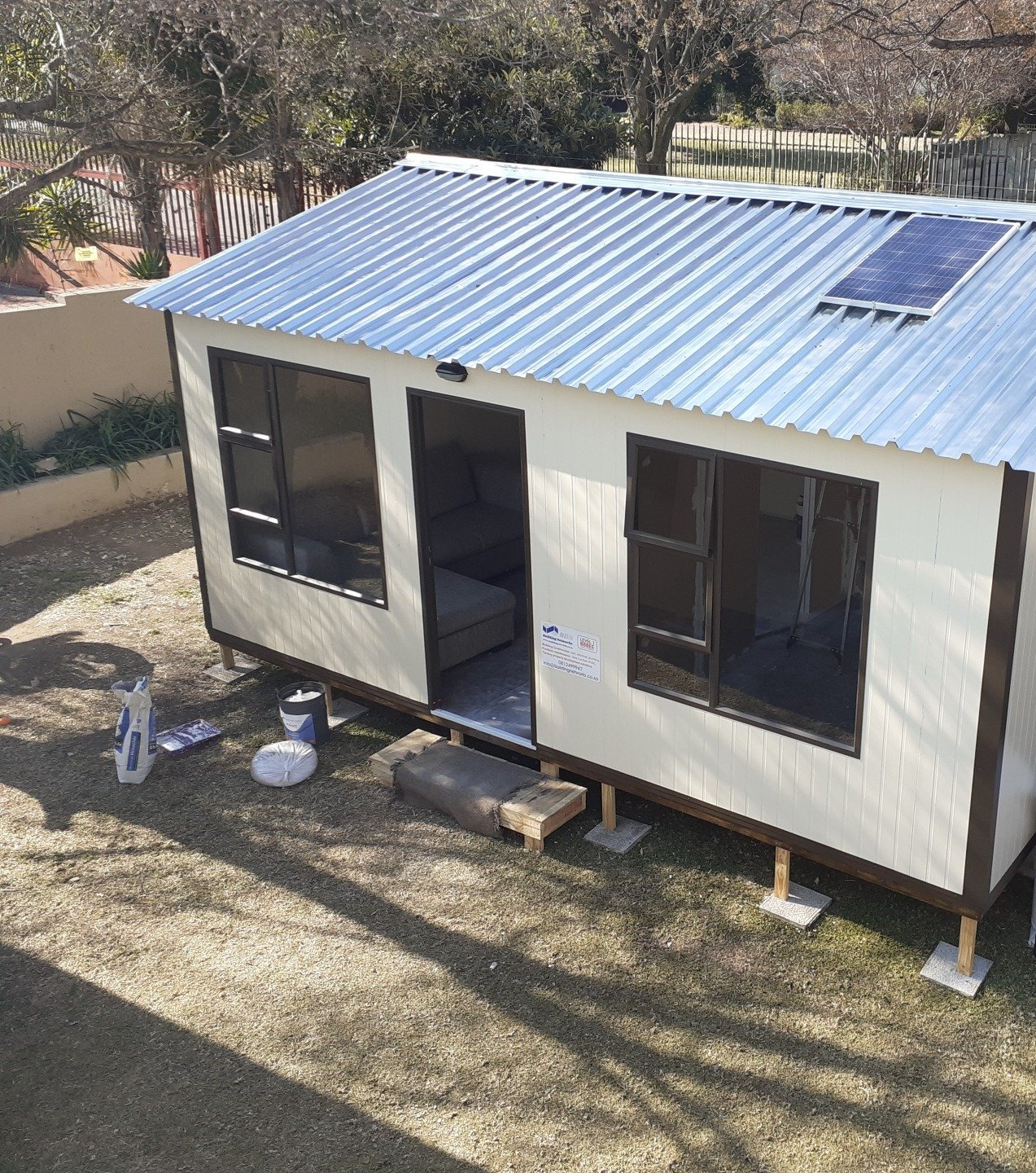A small house with a metal roof and solar panels on the roof.