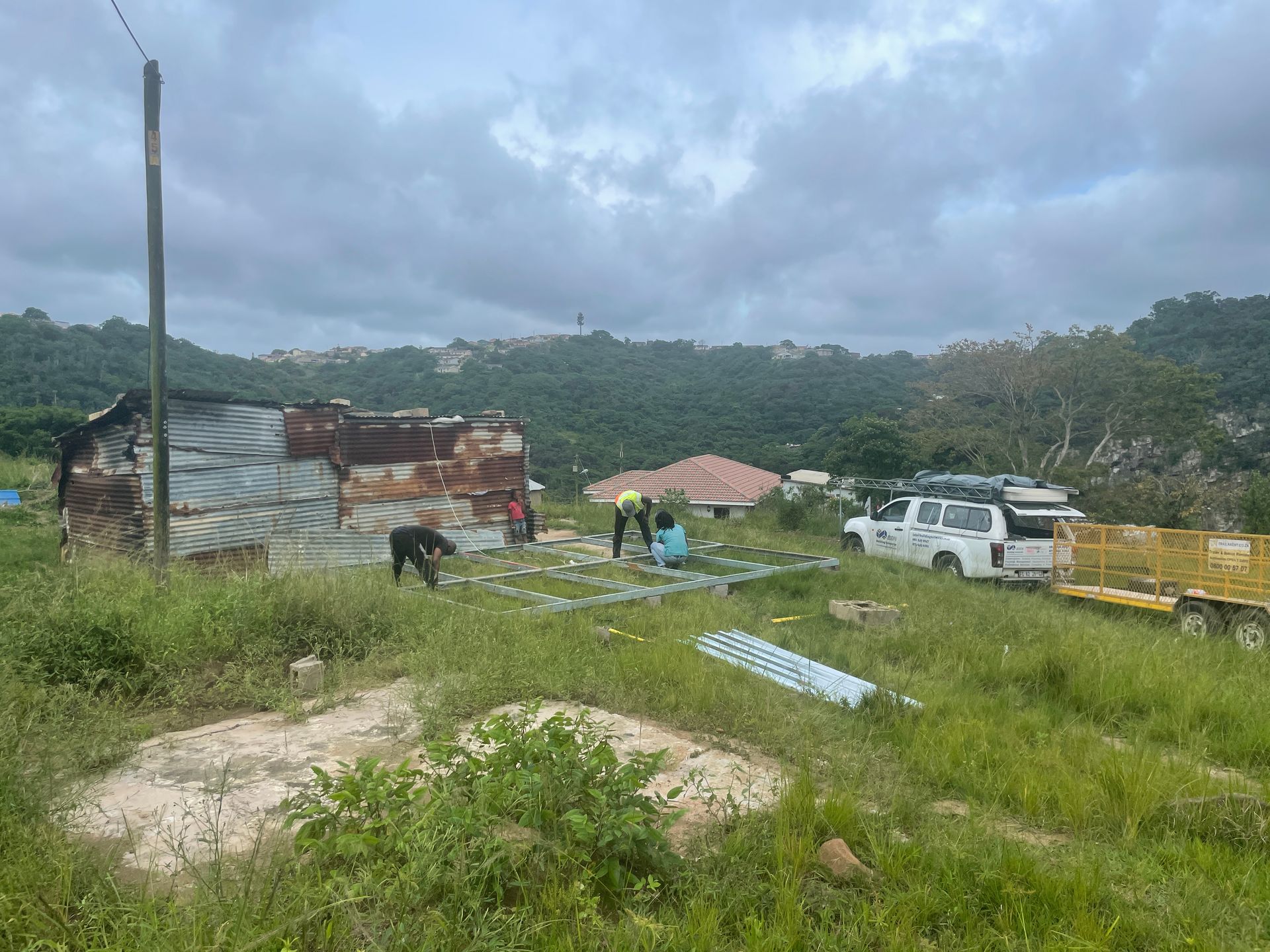 A group of people are working on a roof in a field.