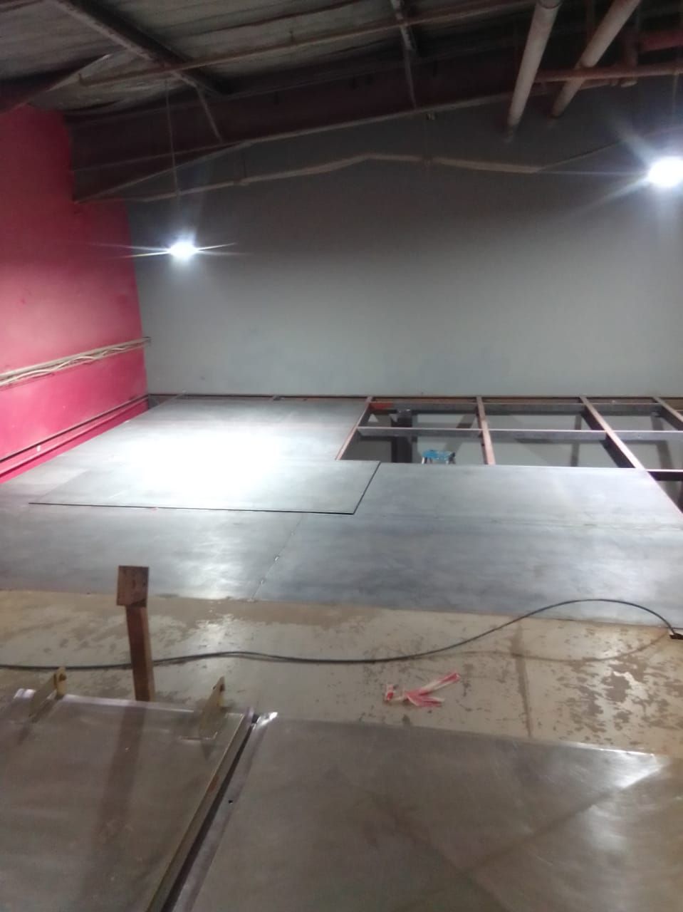 A large room with a concrete floor and a red wall