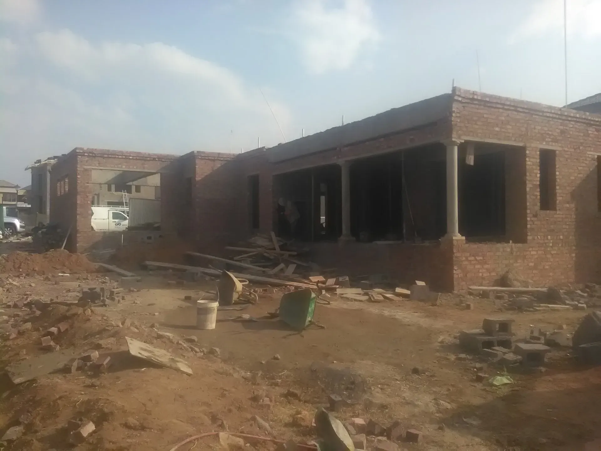A brick building is being built in a dirt field.