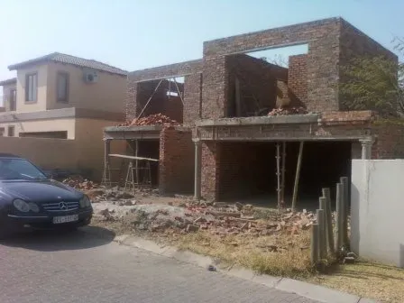 A car is parked in front of a building under construction