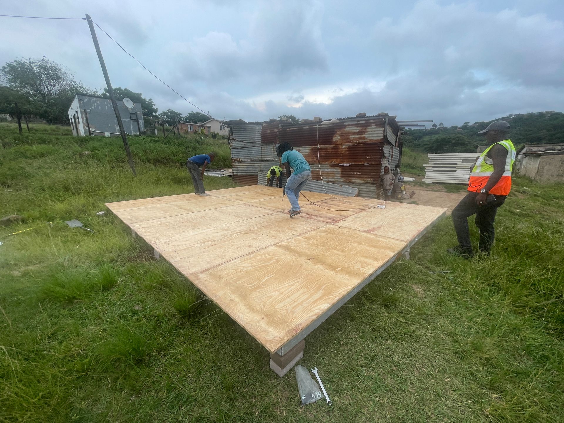 A group of people are working on a wooden platform in a field.