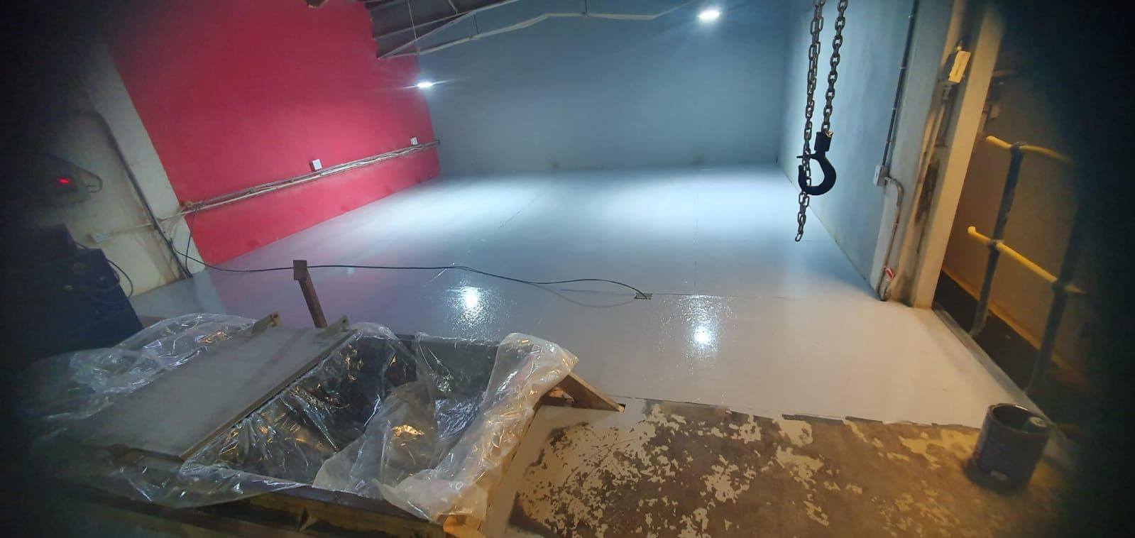 A dark room with a white floor and a red wall.