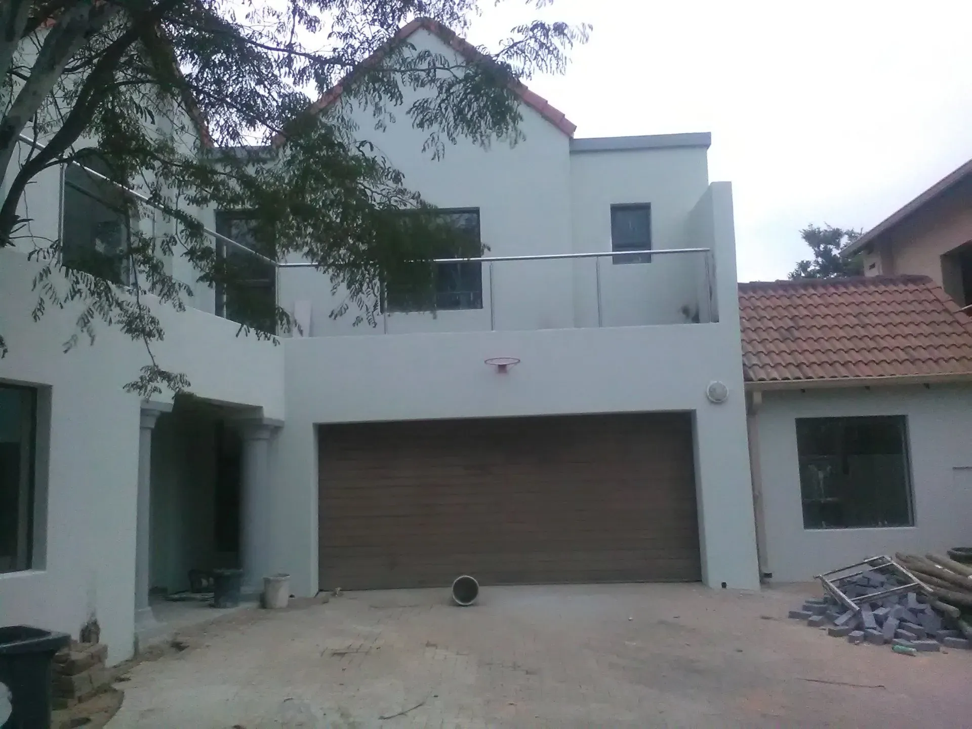 A white house with a brown garage door and a balcony