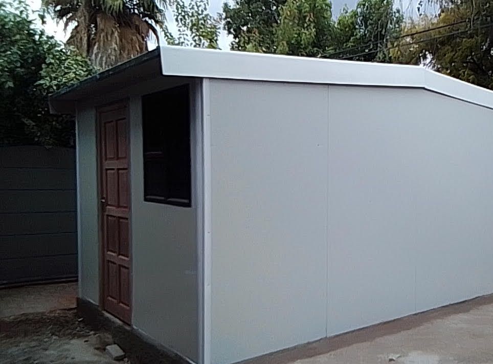 A small white building with a wooden door and window.