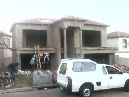 A white truck is parked in front of a house under construction