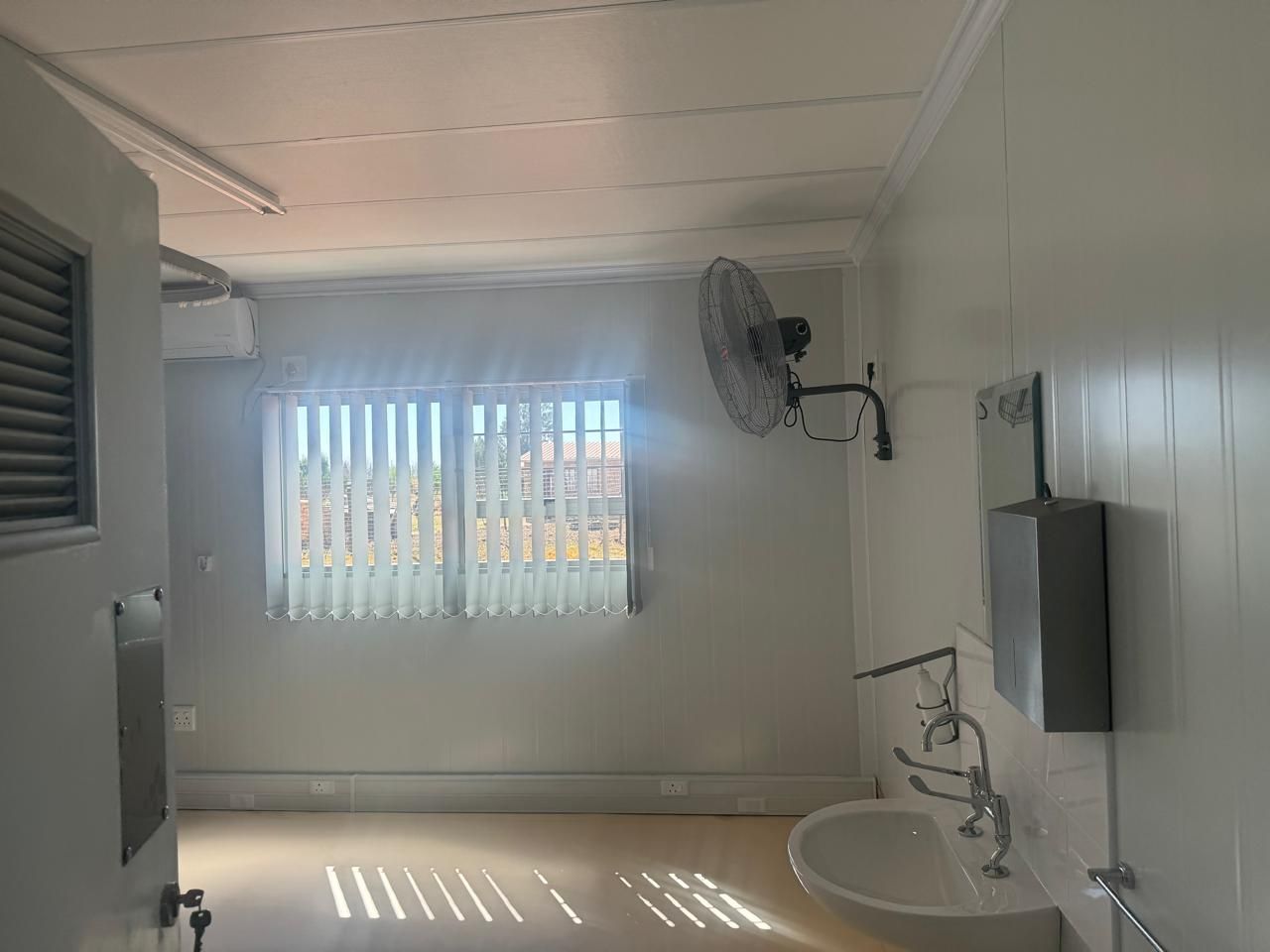 A bathroom with a sink and a fan on the wall.