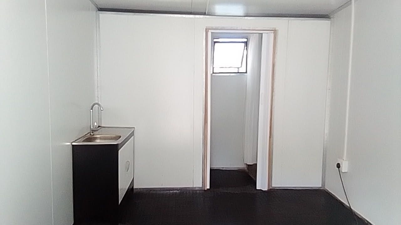 An empty room with a sink and a door leading to a bathroom.