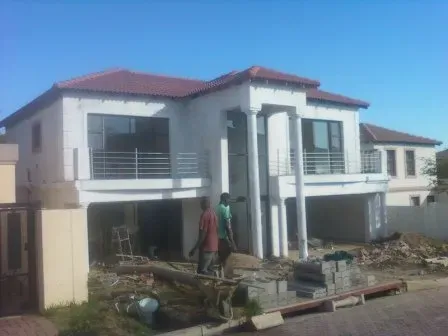 A large white house with a red tile roof is being built