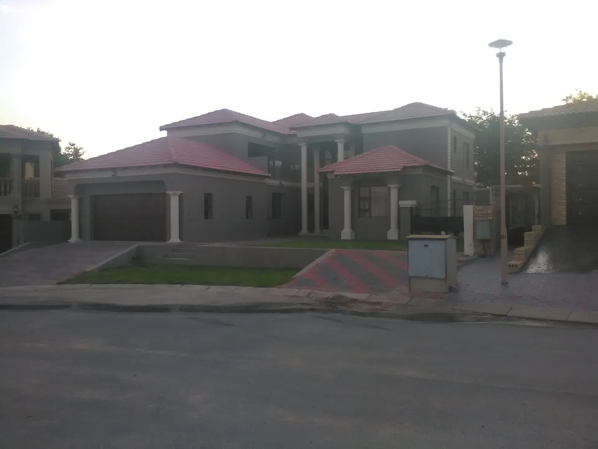 A large house with a red roof is sitting on the side of the road.