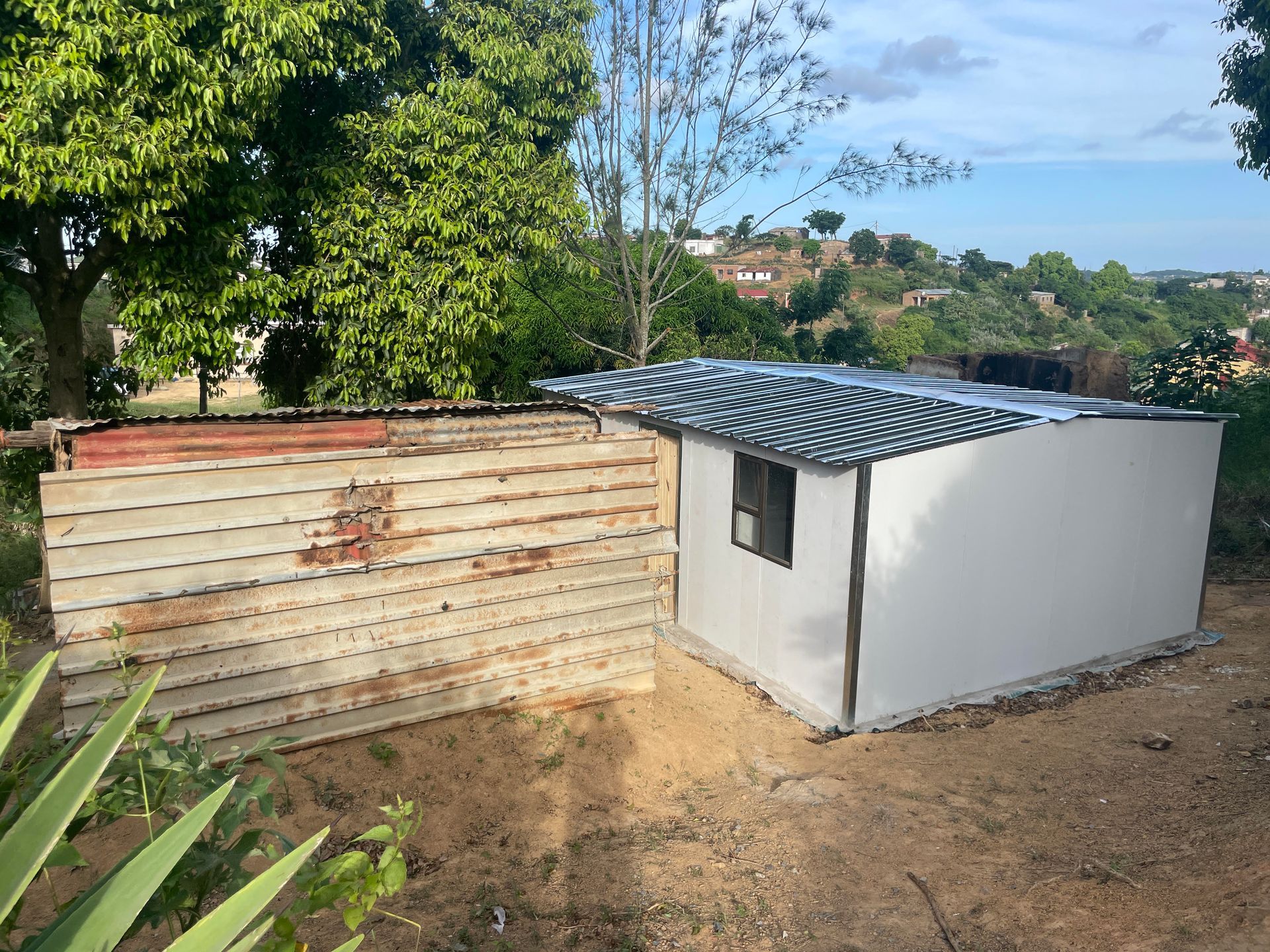 A small white shed is sitting next to a wooden fence.