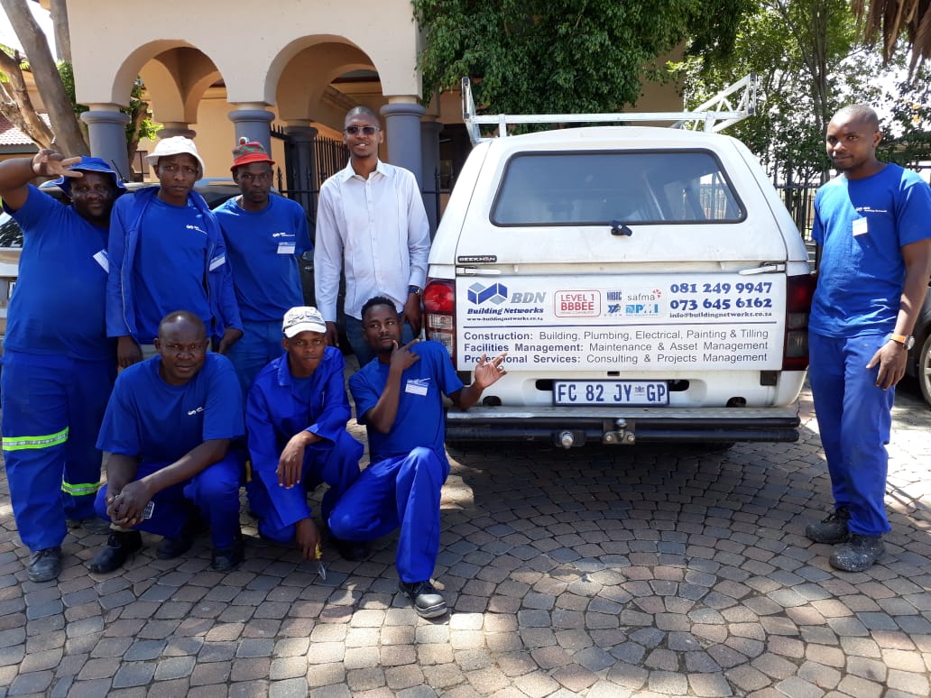A group of men are posing for a picture in front of a white truck