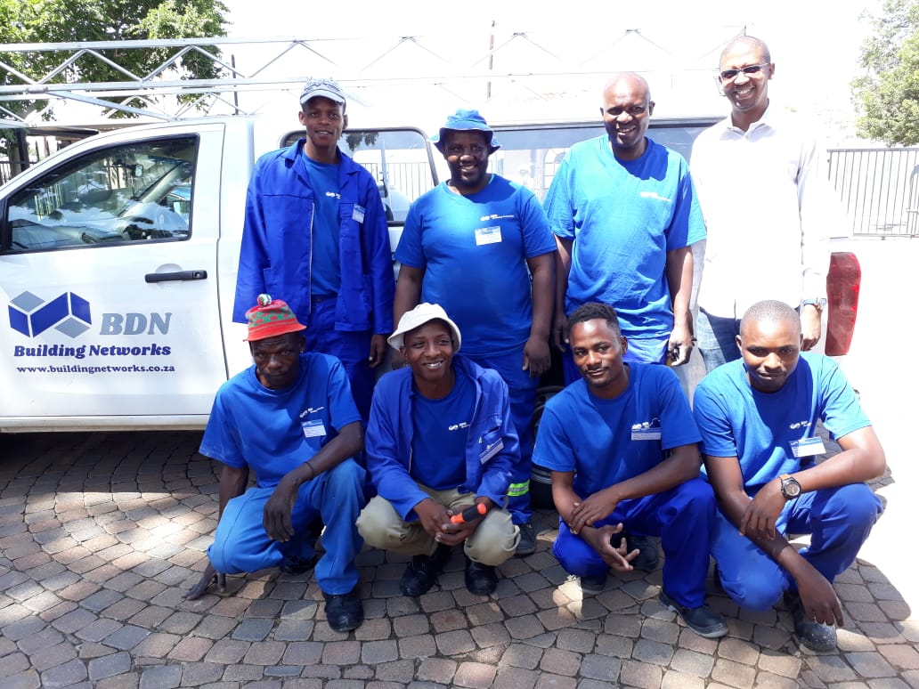 A group of men are posing for a picture in front of a white van that says bdn