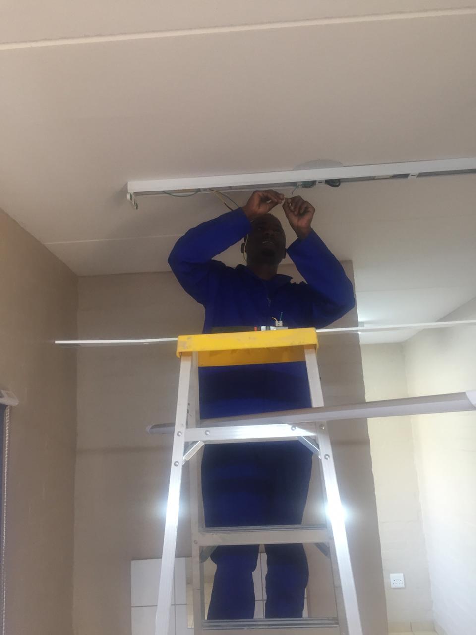 A man on a ladder working on a light fixture