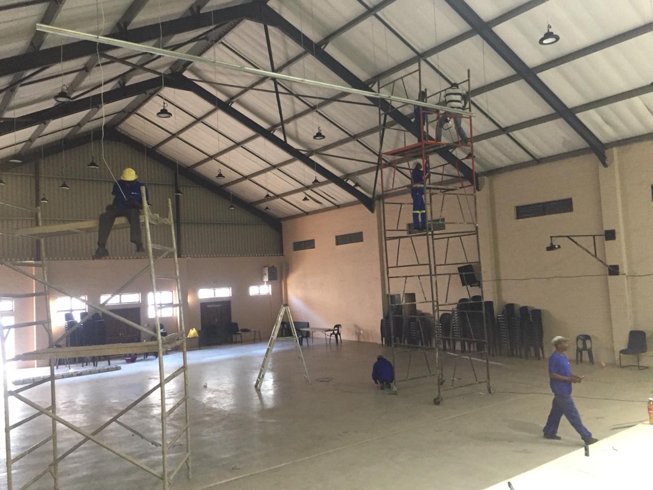 A group of people are working on the ceiling of a building.