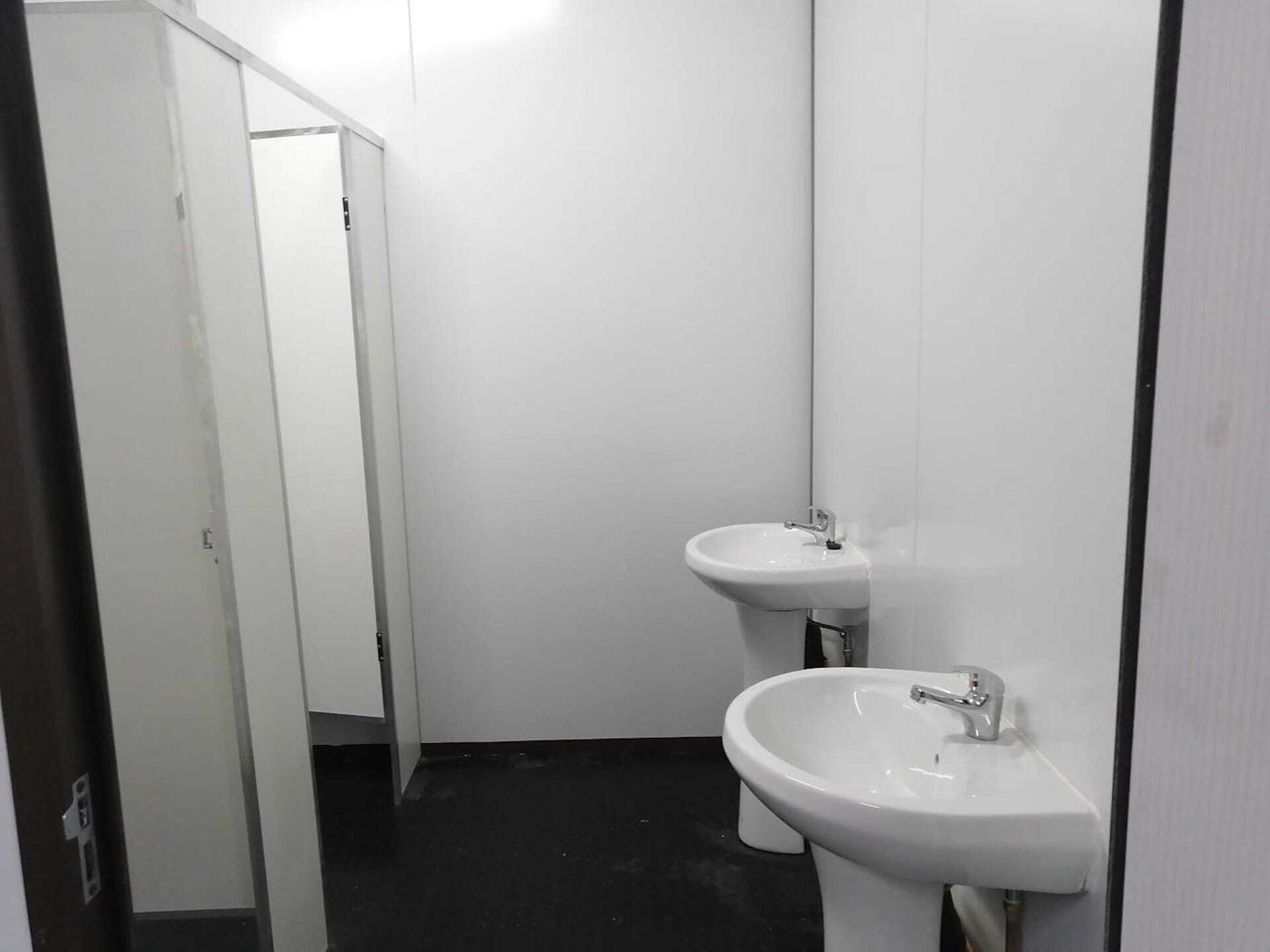 A bathroom with two sinks and a cubicle.