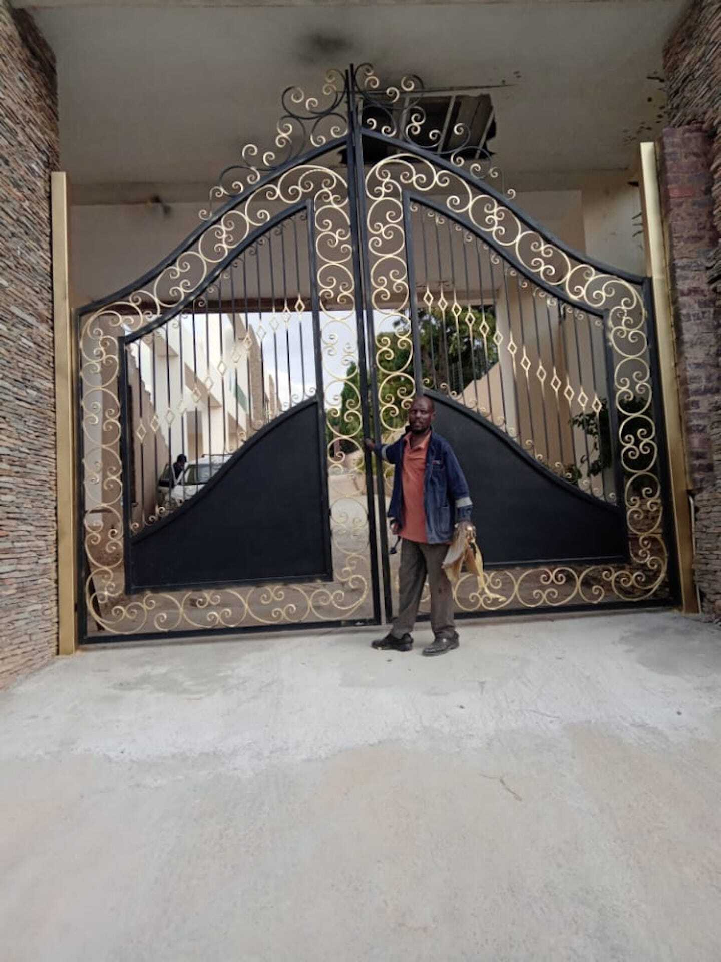 A man is standing in front of a wrought iron gate.