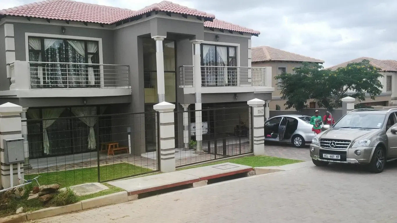 A car is parked in front of a large house.