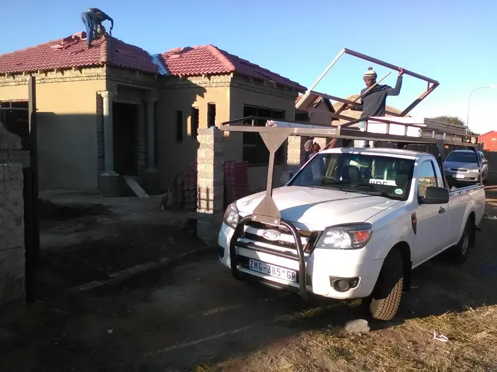 A white truck is parked in front of a house under construction.