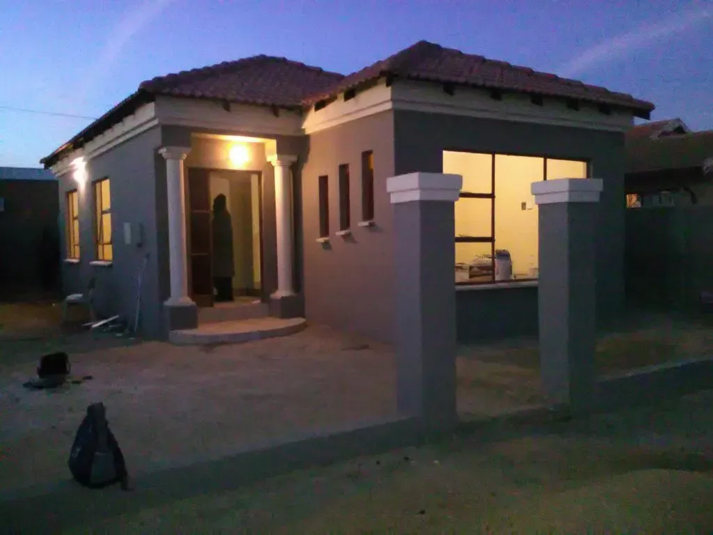 A small house with a red tile roof is lit up at night.
