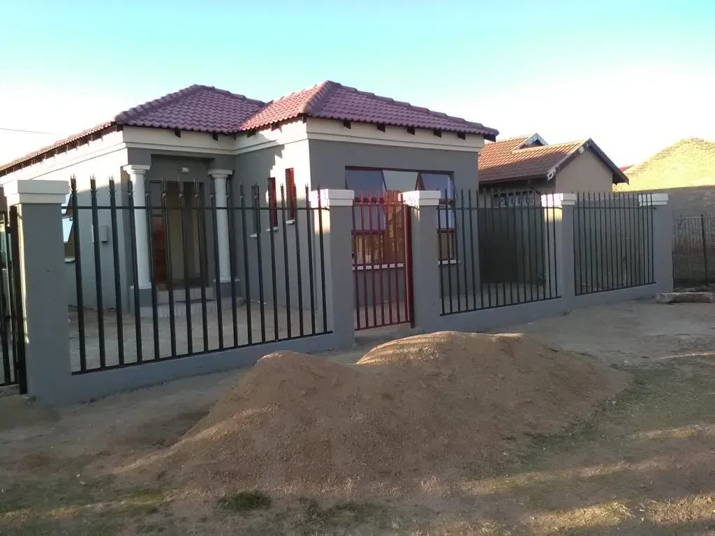 A house with a fence around it and a pile of dirt in front of it