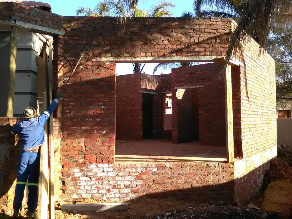 A man is standing in front of a brick building under construction