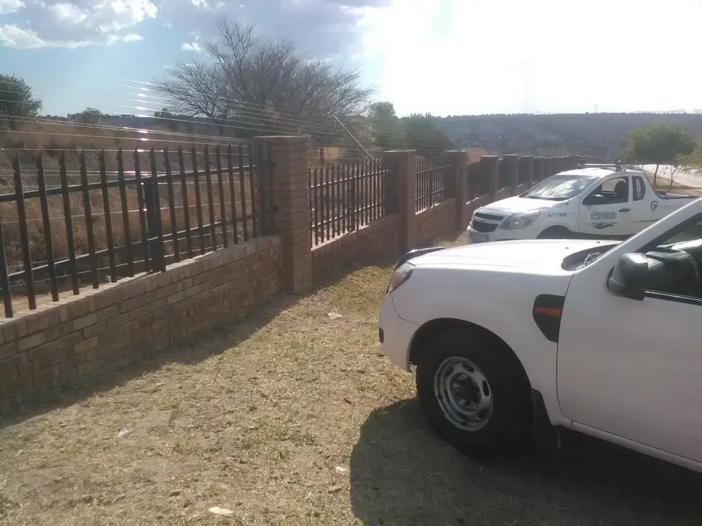 A white truck is parked in front of a fence.
