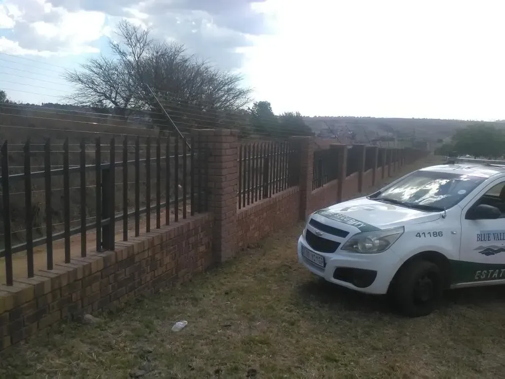 A white car is parked in front of a fence.