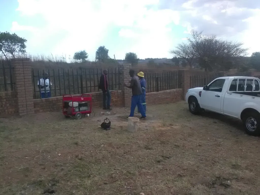 A white truck is parked in the grass next to a generator.
