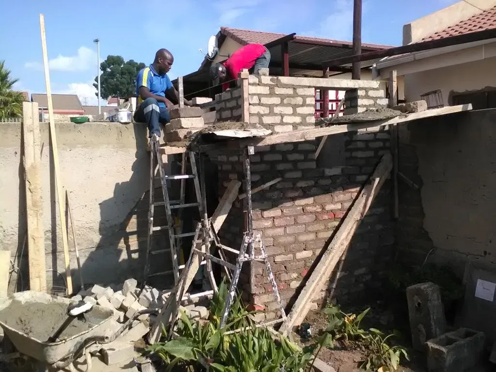 A group of construction workers are working on a brick wall