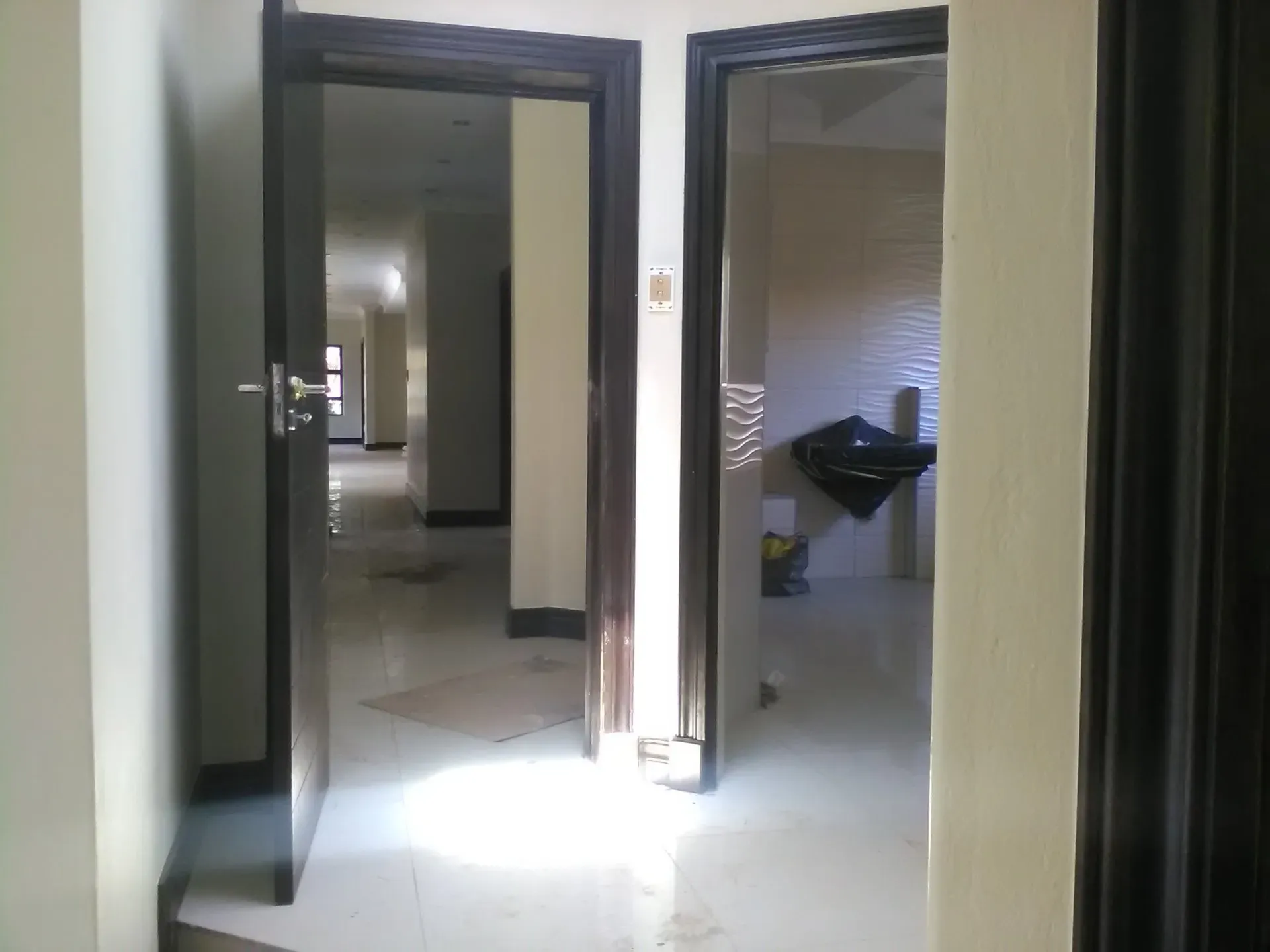 A hallway with two doors open leading to a bathroom