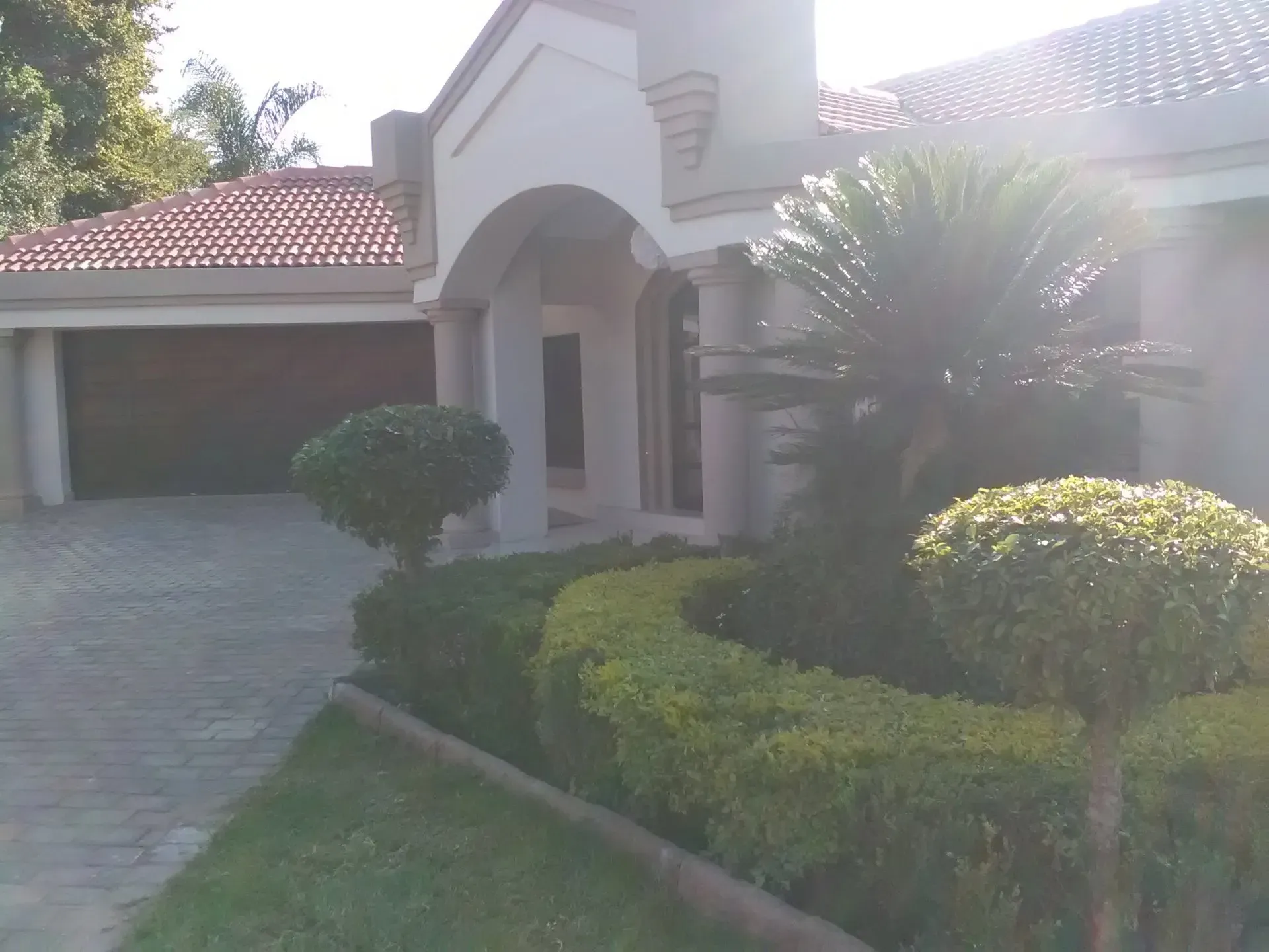 A large white house with a red tile roof and a driveway