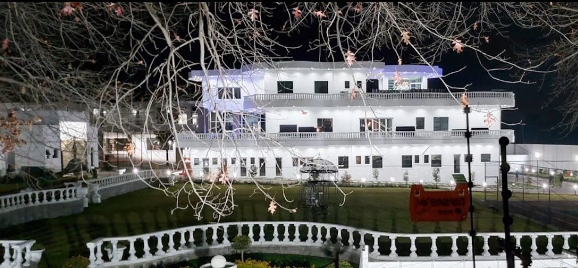 A large white building with a bridge in front of it at night.