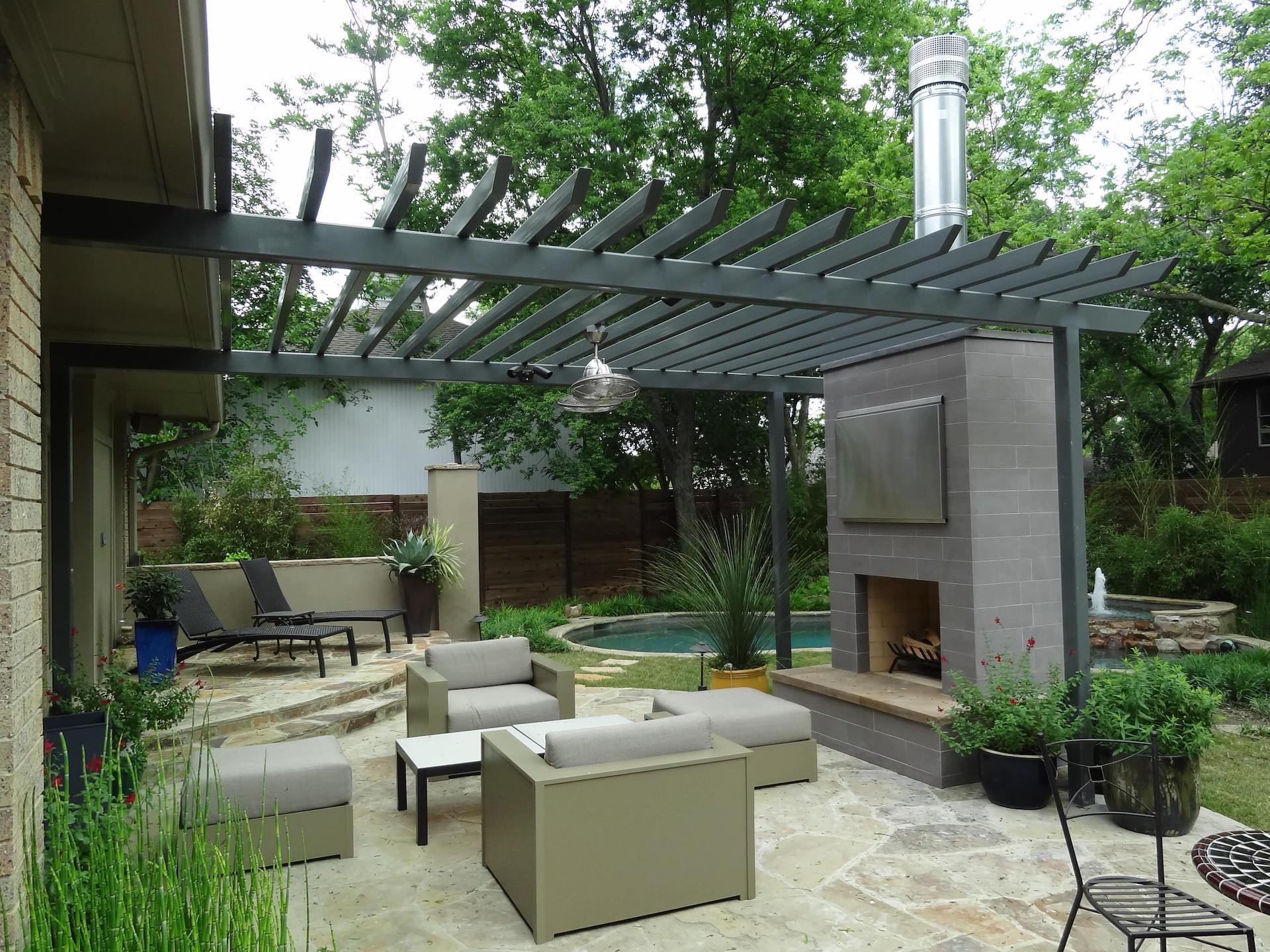 A patio with furniture and a fireplace under a pergola