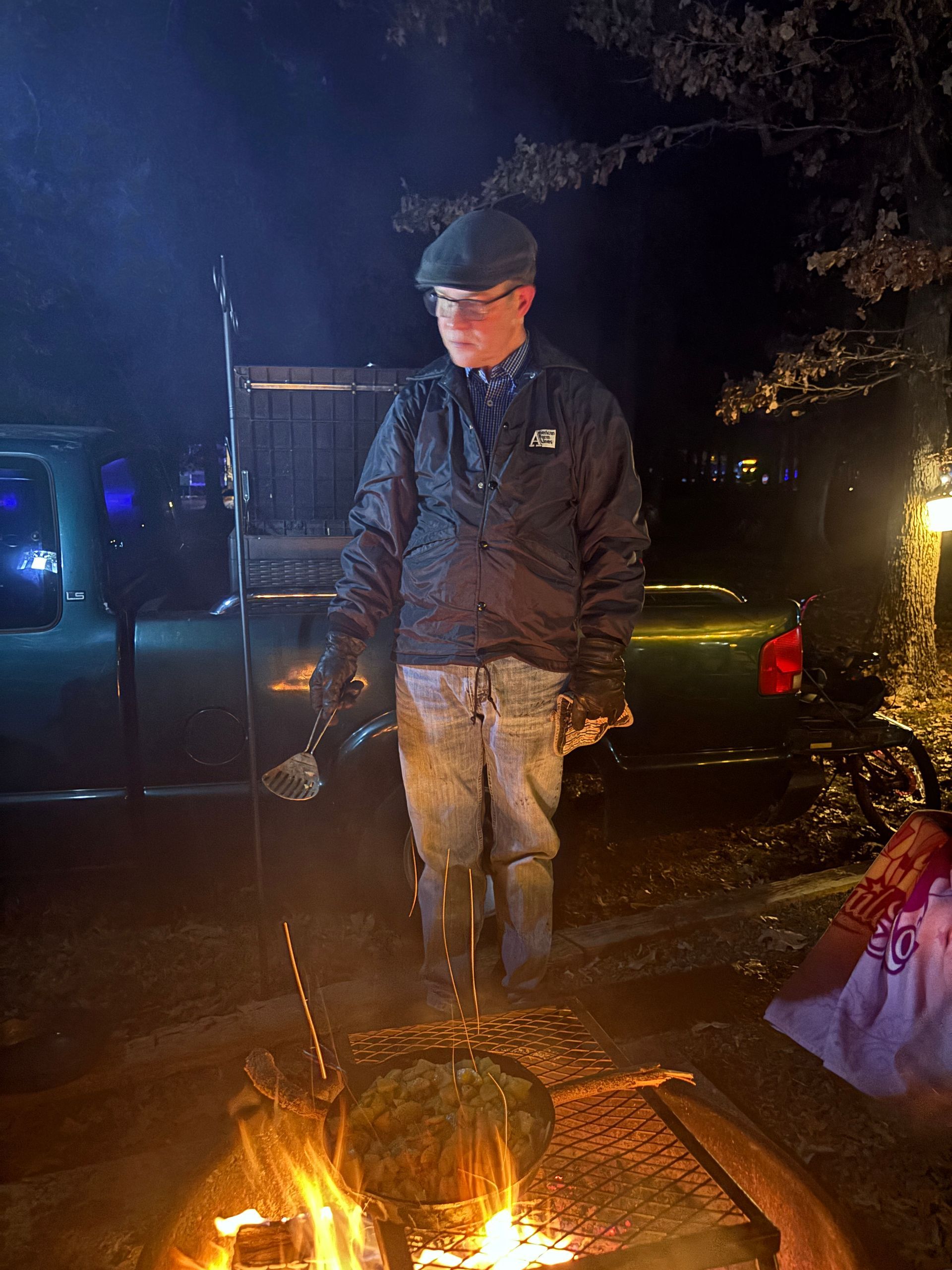 Fried Taters over fire with man bundled up holding spatula