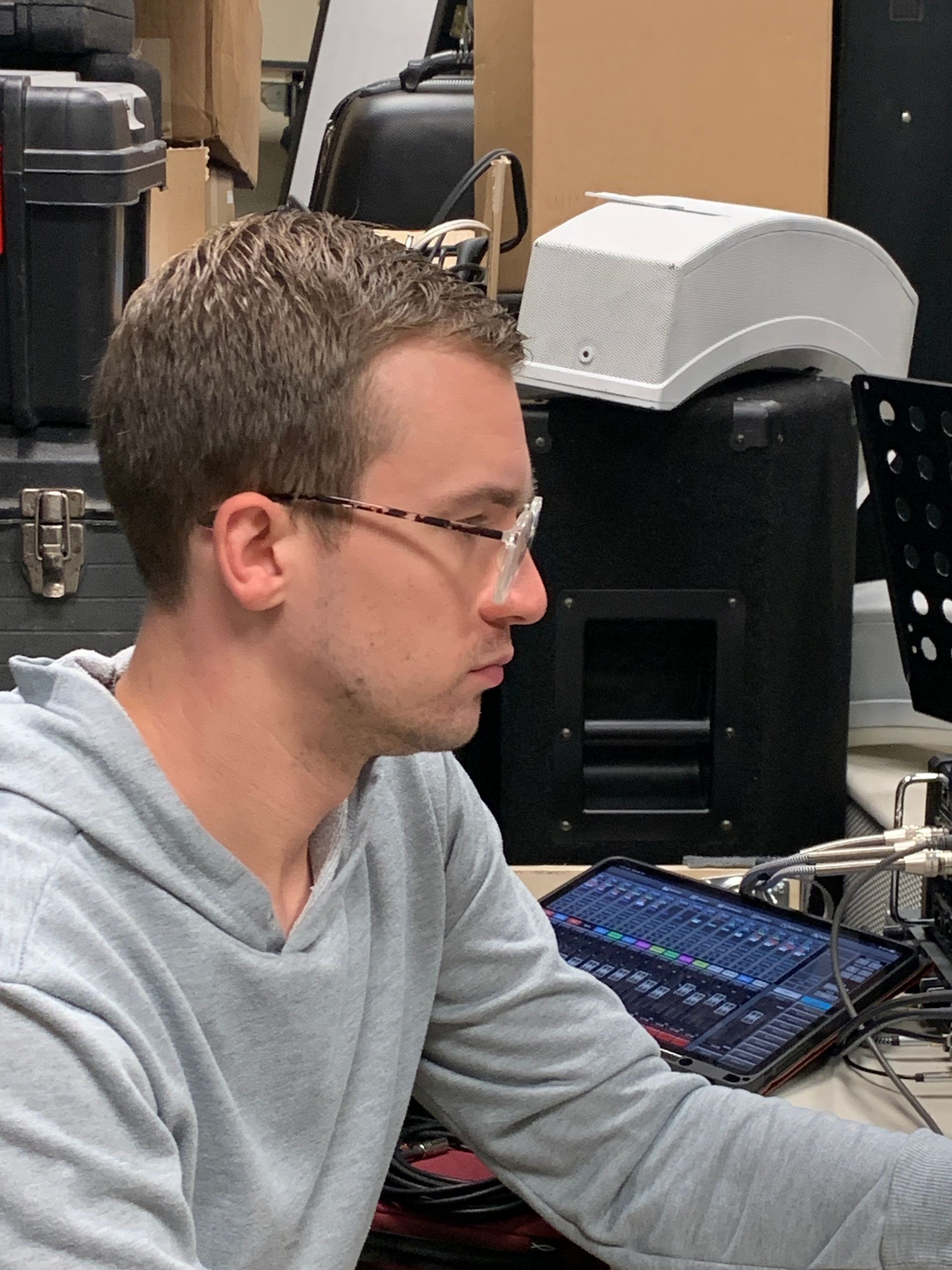 A man wearing glasses is sitting at a desk with a tablet