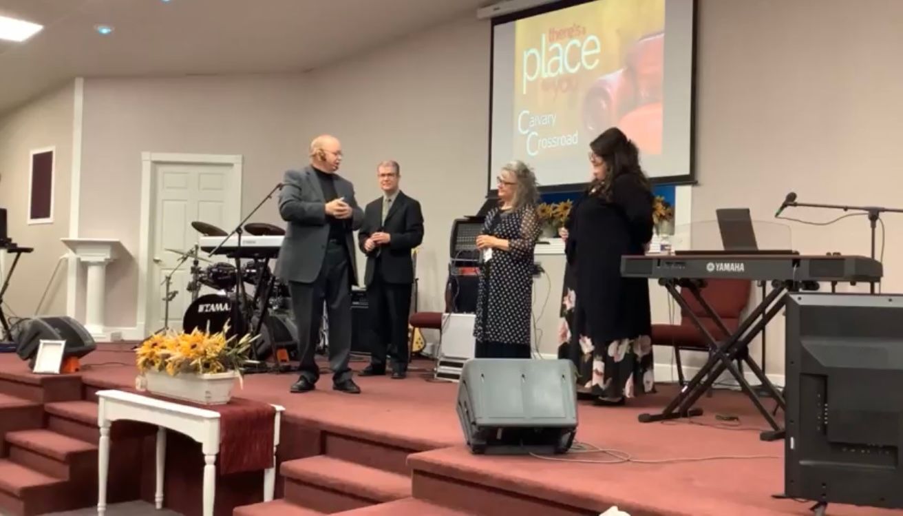 A group of people are standing on a stage in front of a screen that says place