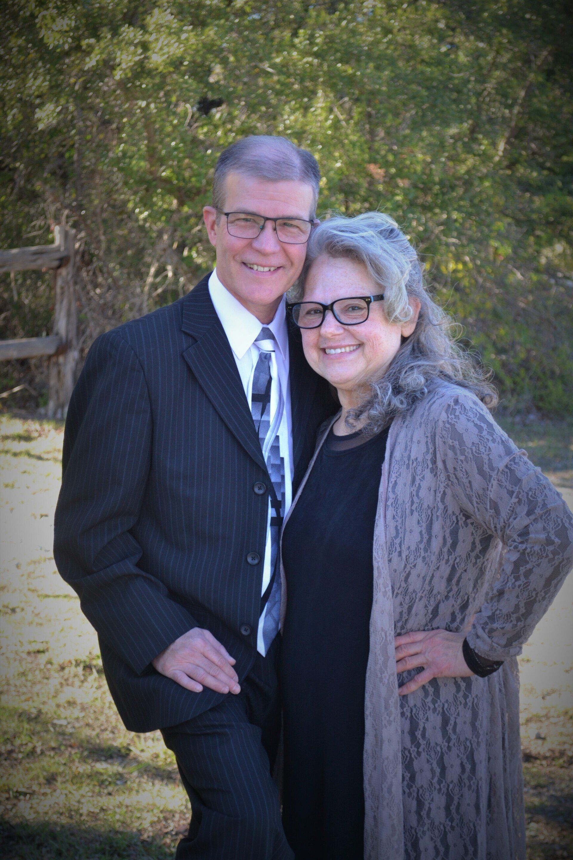 A man in a suit and tie is standing next to a woman in a black dress.