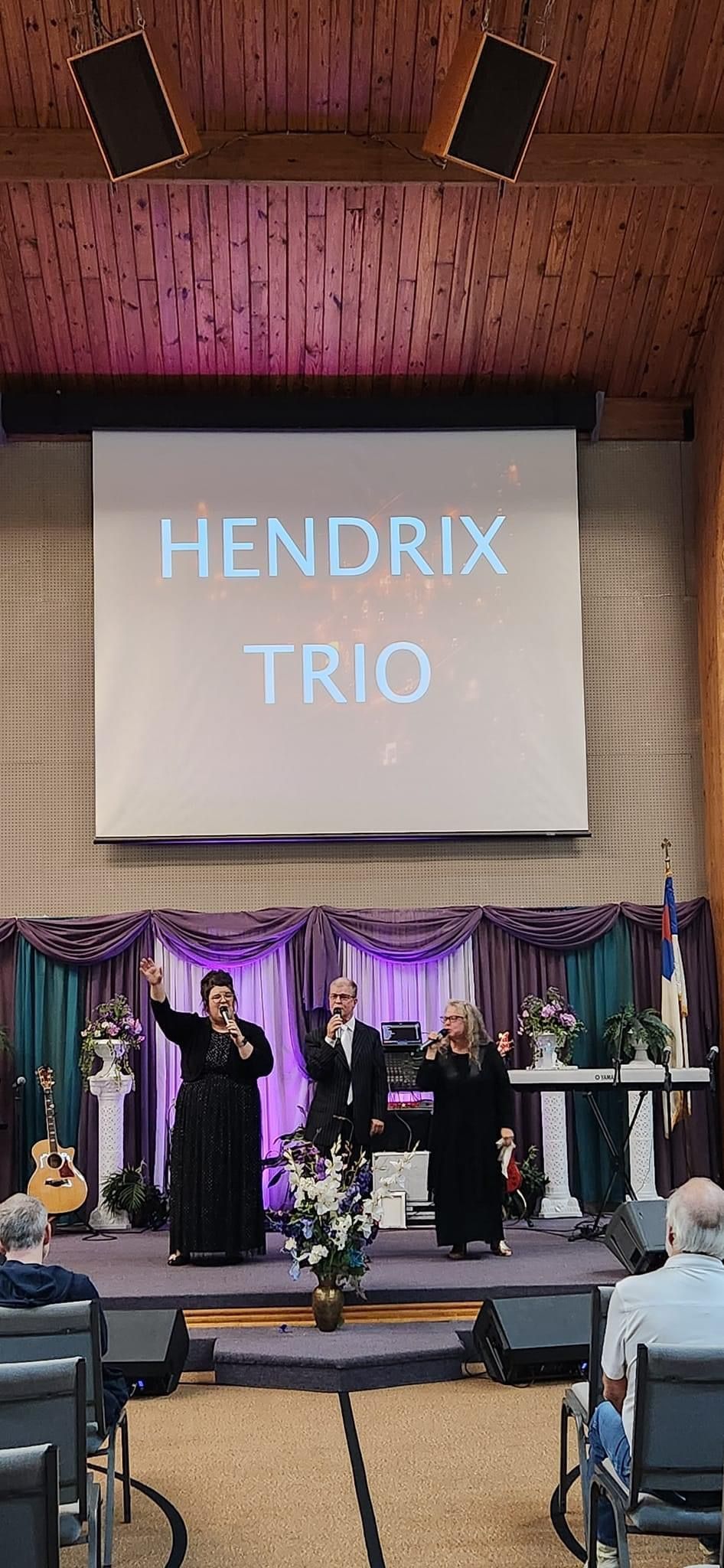 trio on stage raising hands and singing