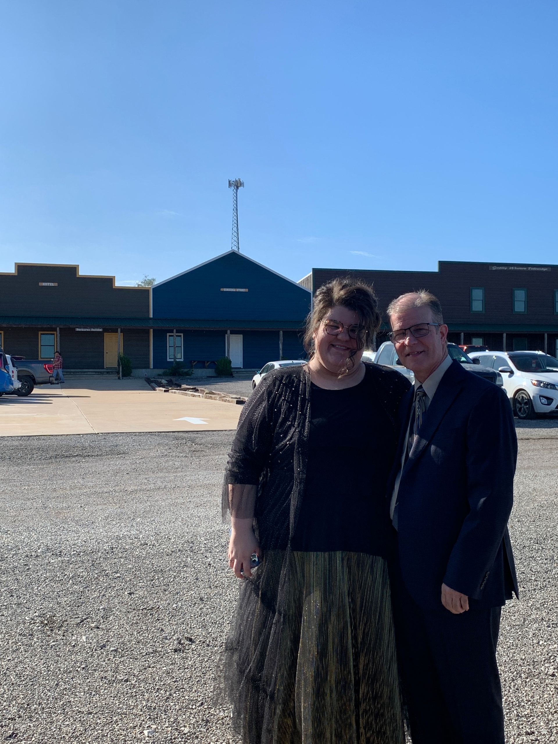 A man and a woman are posing for a picture in front of a building.