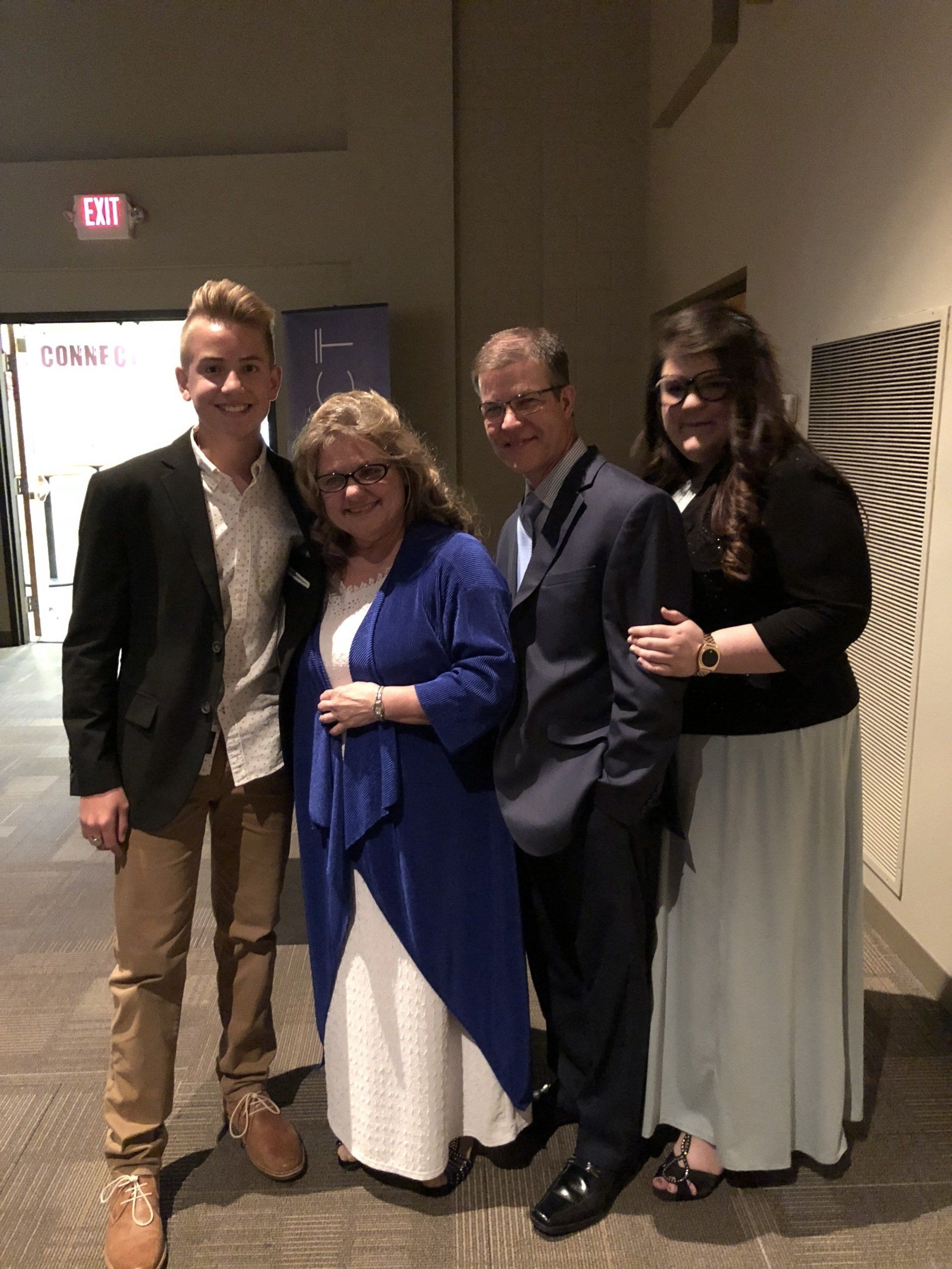 A group of people posing for a picture in front of an exit sign