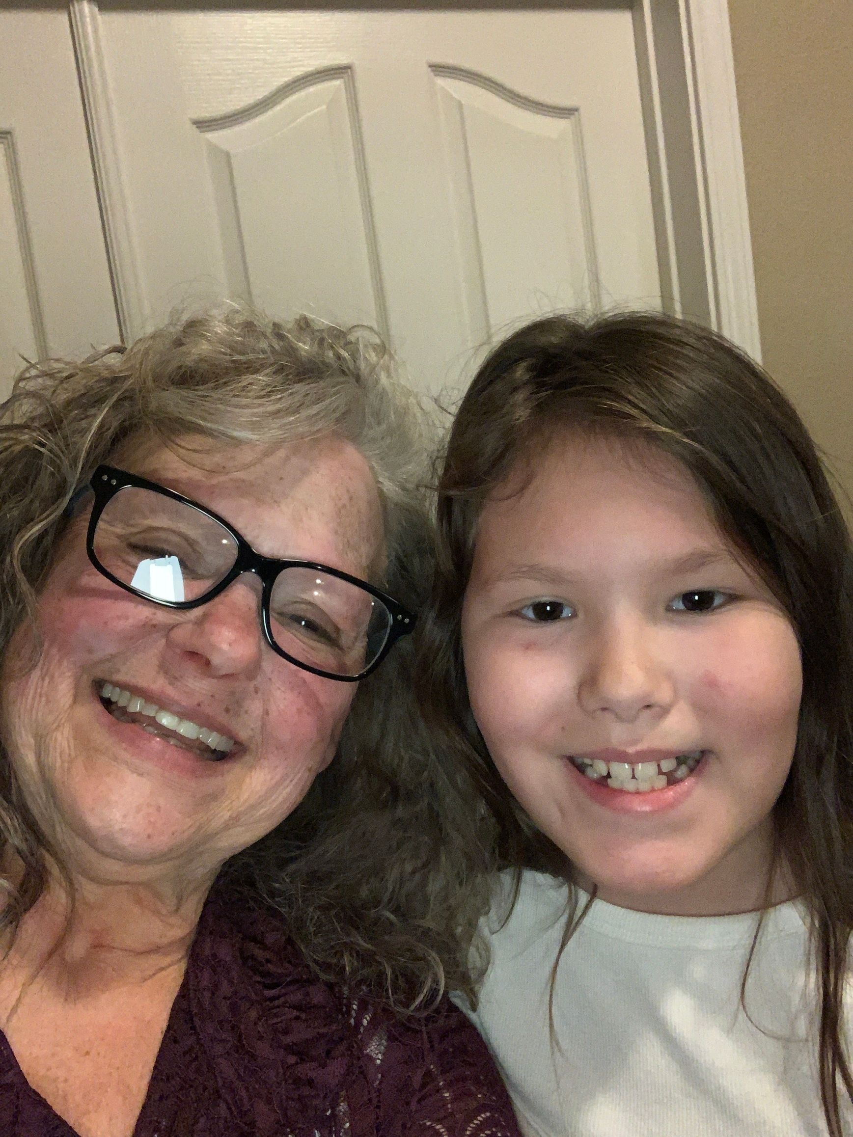 A woman wearing glasses is posing for a picture with a young girl.