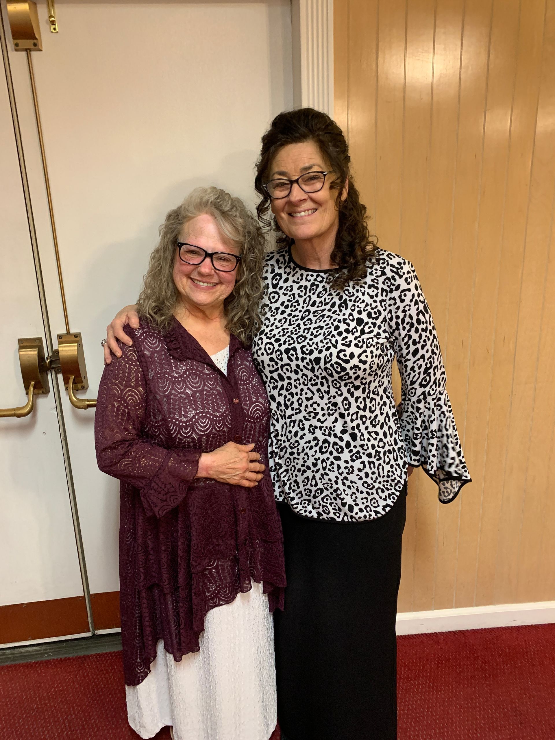 Two women are posing for a picture in front of a door