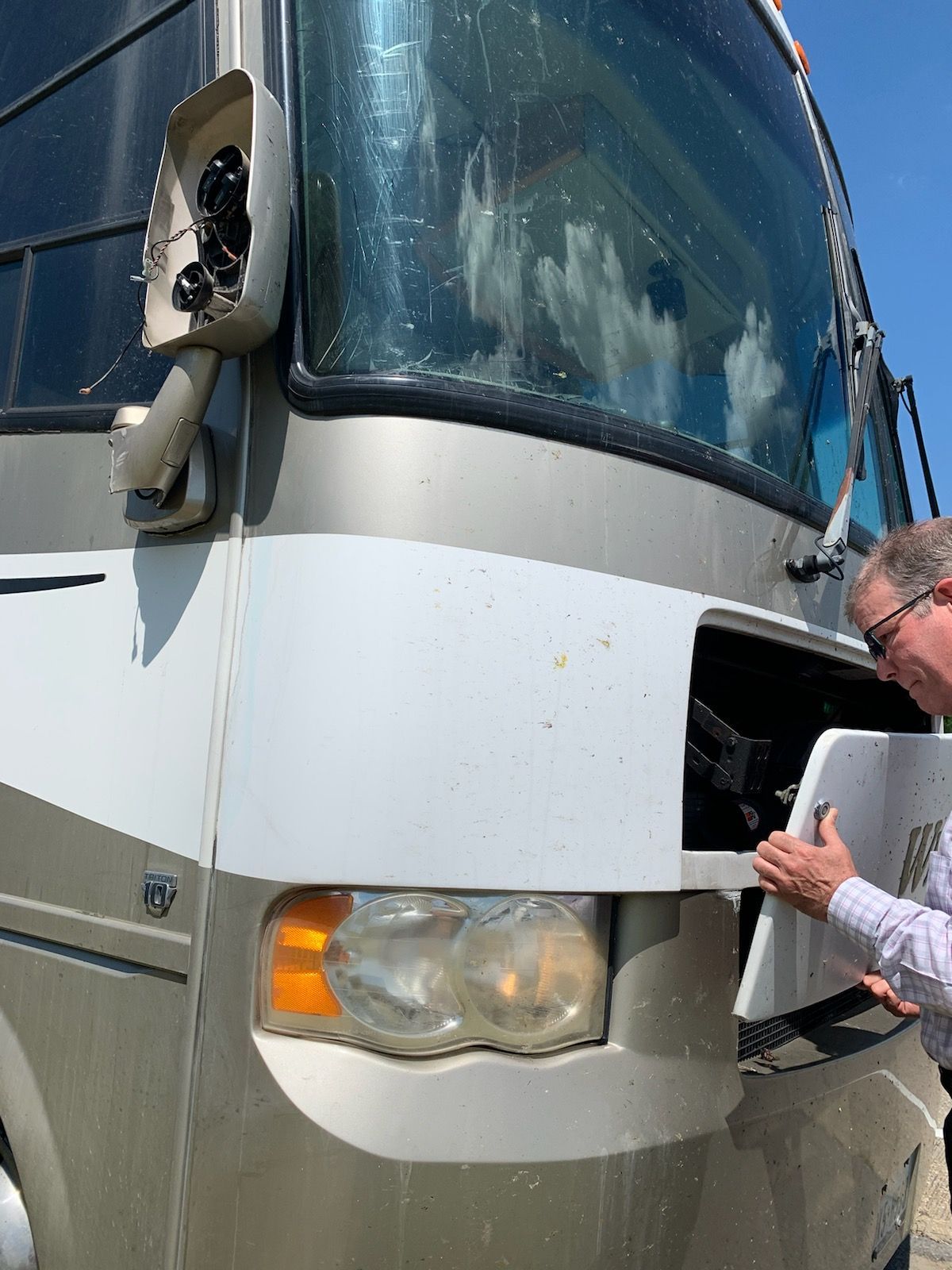 A man is working on the front of a rv.