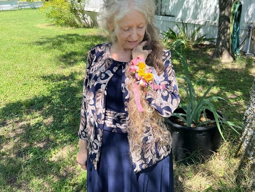 lady with long red hair loking down ant corsage outside