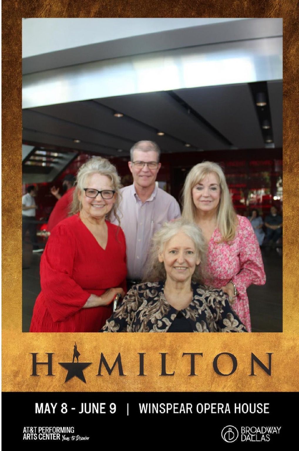 A group of people posing for a photo in front of a hamilton poster