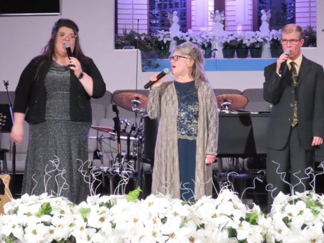 A group of people singing into microphones on a stage