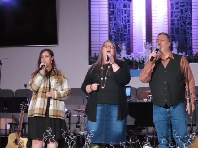 A group of people singing into microphones on a stage