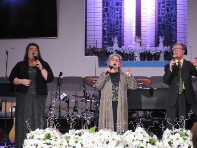 A group of people singing into microphones on a stage