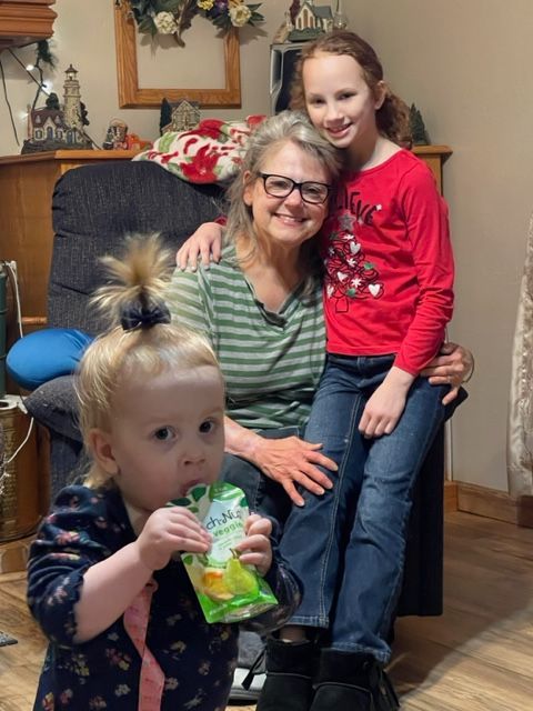 A woman is sitting in a chair with two children.